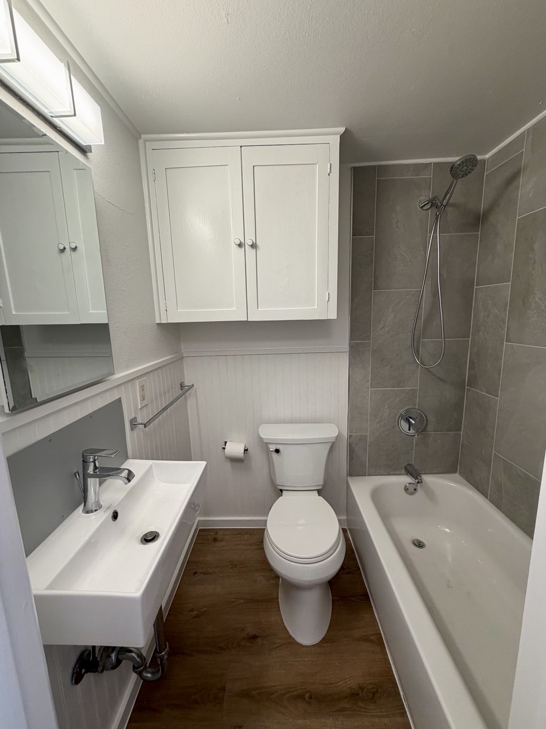 Fully renovated bathroom with modern white vanity and tiled tub-shower