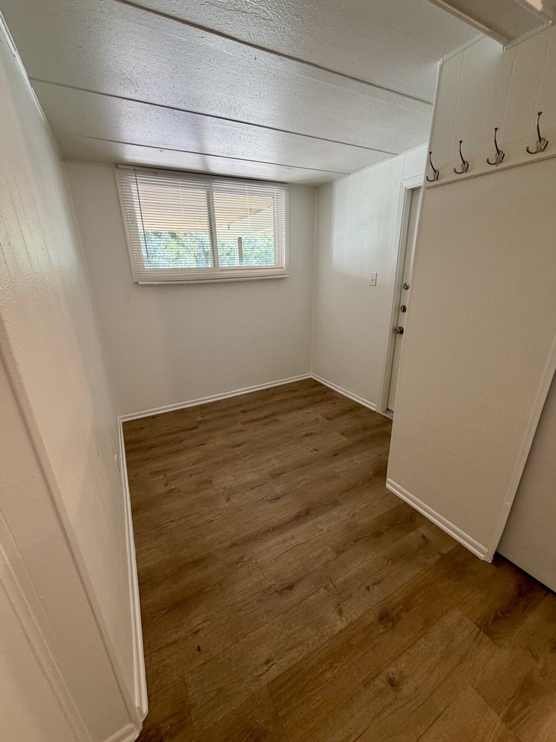 Entry room with coat hooks, window and wood-look flooring