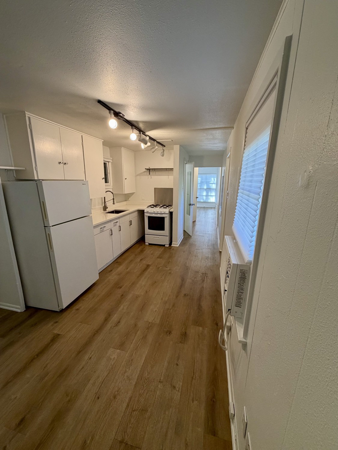 Kitchen and hallway view showing refrigerator, gas range and sink