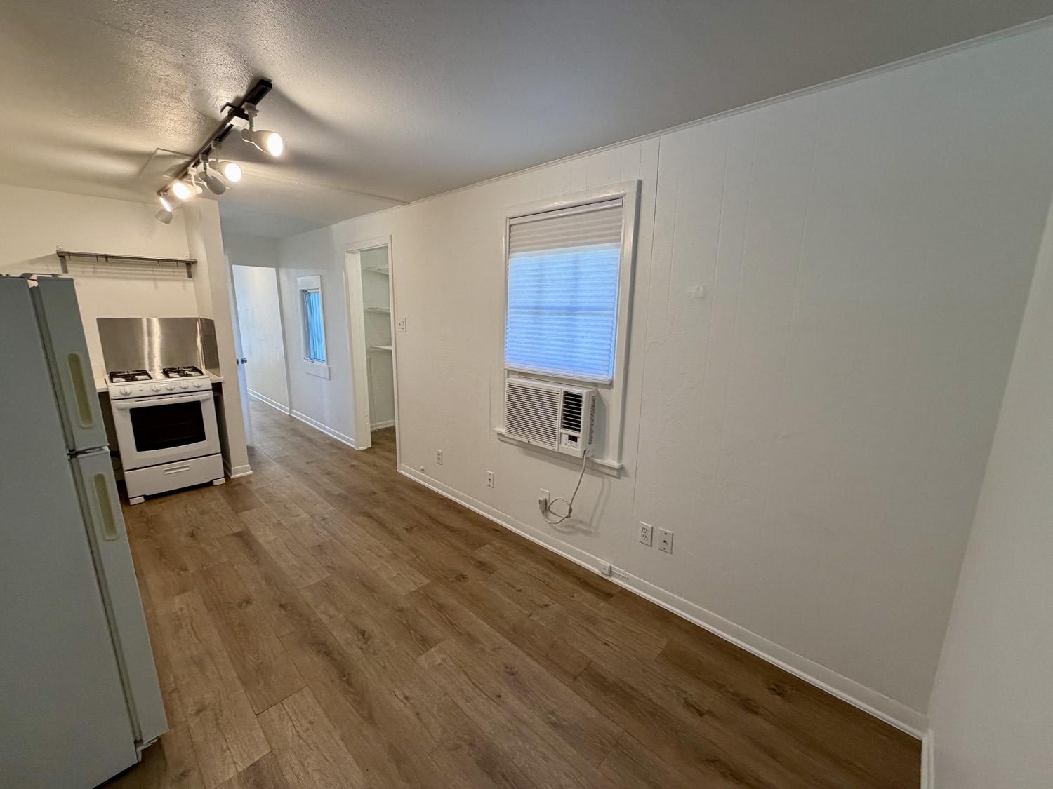 Open kitchen and living area with gas range, full-size refrigerator and wood-look flooring