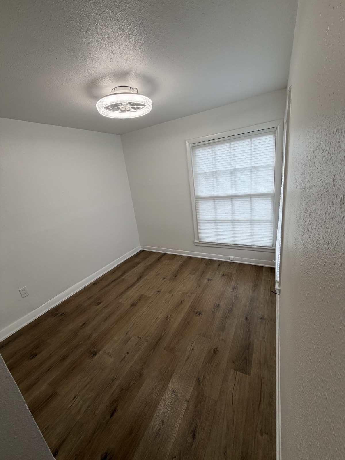 Bedroom with new ceiling light fixture and large window, hardwood-look flooring