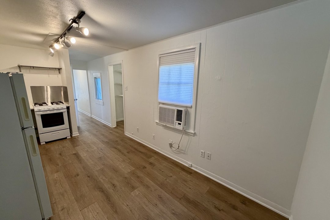 Open kitchen and living area in Unit C with gas range, full-size refrigerator and wood-look flooring