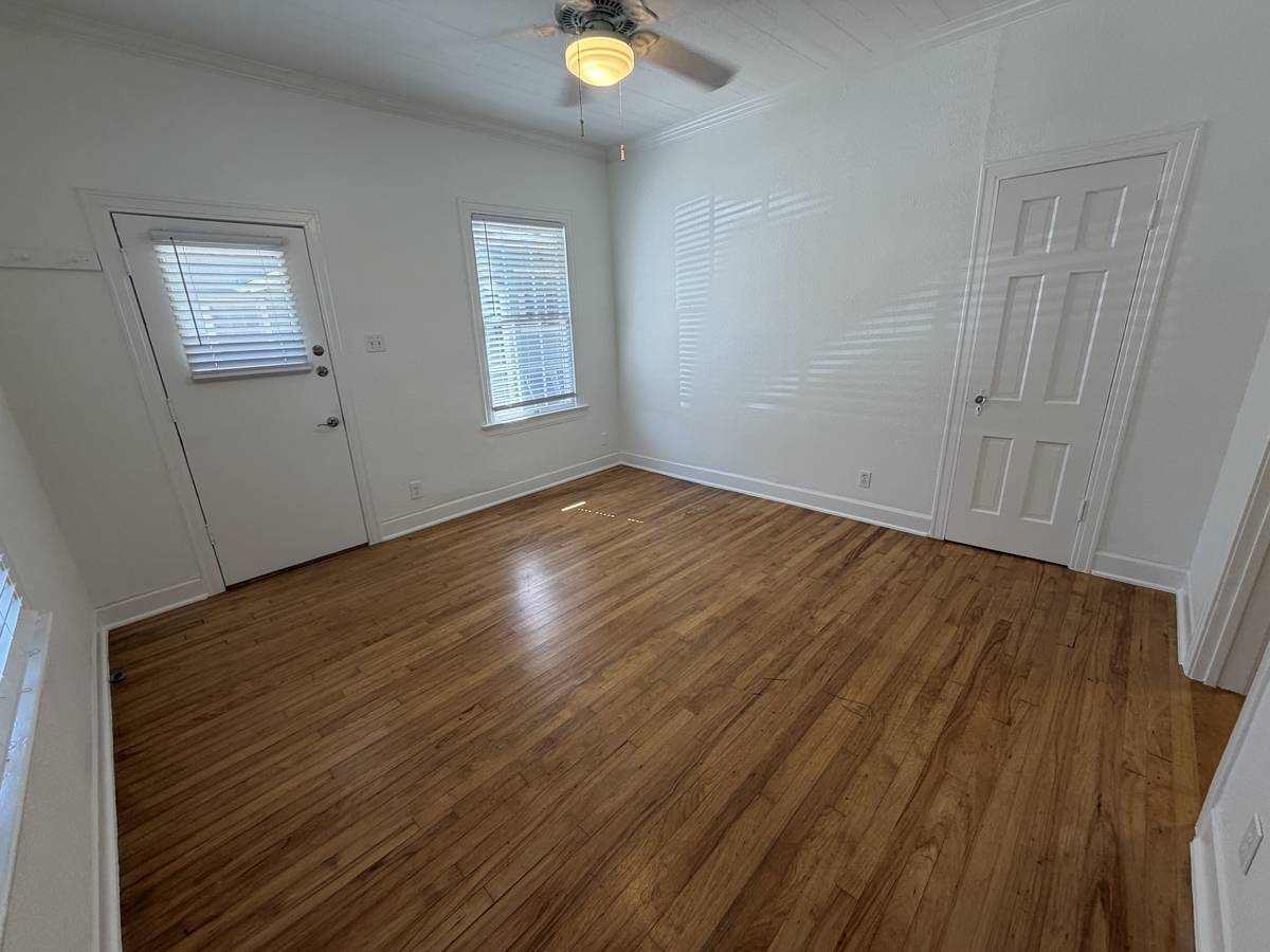 Living room of Unit D at 1505 W. 12th Street — 13 by 13 feet with original hardwood floors, ceiling fan and a private exterior door